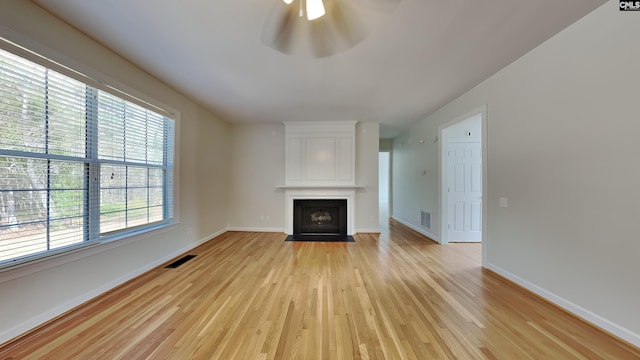 unfurnished living room with light wood-type flooring, visible vents, baseboards, and a large fireplace