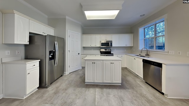 kitchen with a sink, stainless steel appliances, white cabinets, crown molding, and a center island