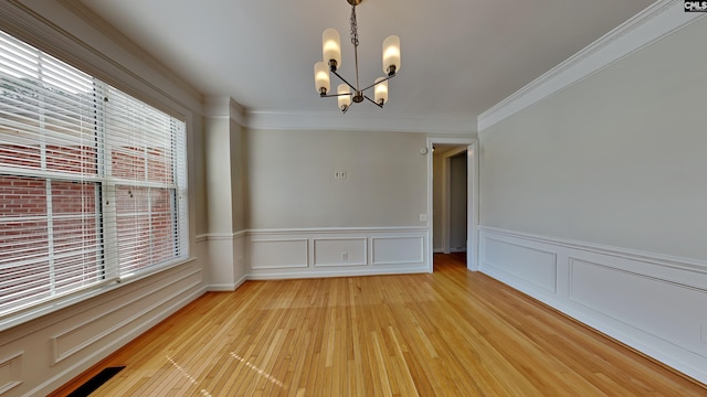 unfurnished room with an inviting chandelier, a decorative wall, crown molding, and light wood-type flooring