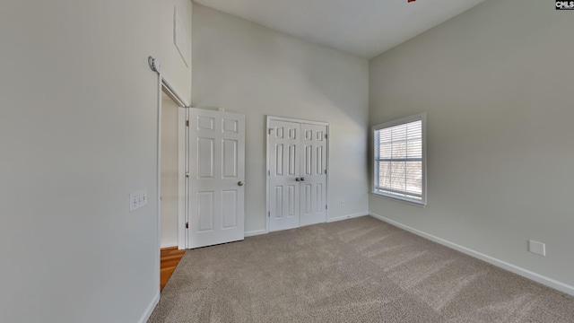 unfurnished bedroom featuring a closet, baseboards, carpet, and a towering ceiling