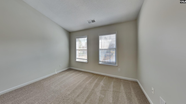 carpeted spare room with visible vents, a textured ceiling, and baseboards