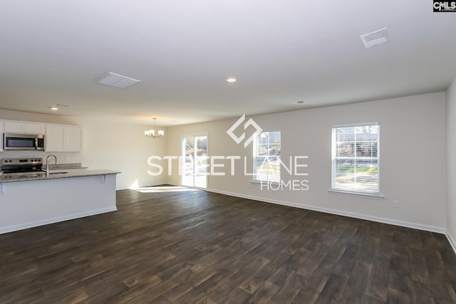 unfurnished living room with a sink, baseboards, a chandelier, recessed lighting, and dark wood-style flooring