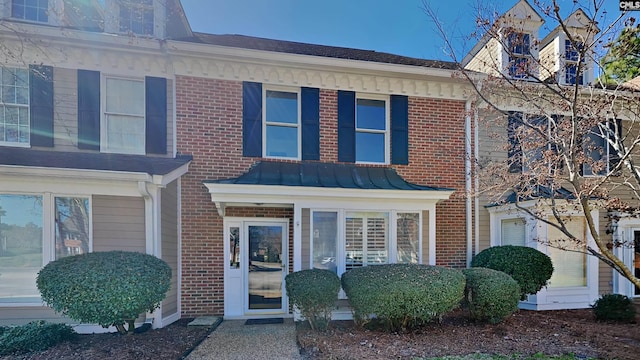 townhome / multi-family property with a standing seam roof and brick siding