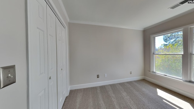 unfurnished bedroom with visible vents, crown molding, baseboards, carpet flooring, and a closet