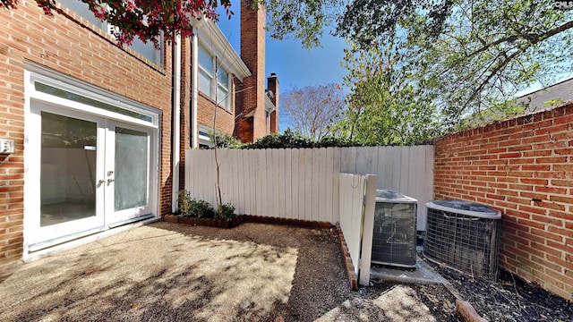 view of yard featuring central AC unit, french doors, fence, and a patio