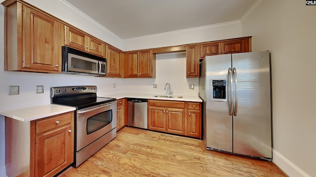 kitchen featuring ornamental molding, a sink, stainless steel appliances, light wood-style floors, and light countertops