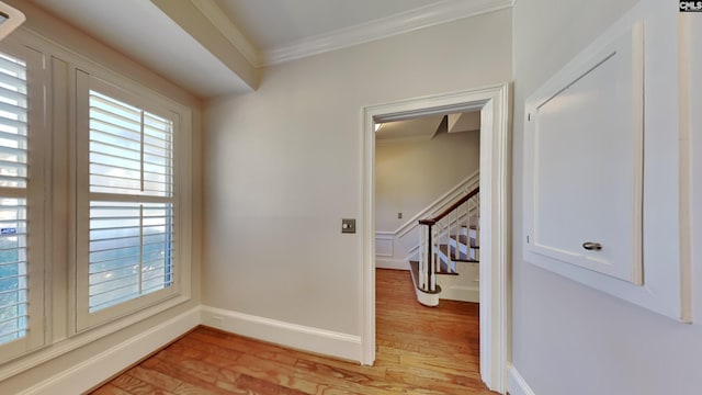 interior space featuring light wood-style flooring, stairs, baseboards, and ornamental molding