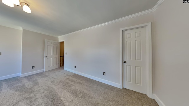 carpeted empty room featuring baseboards and ornamental molding