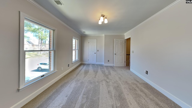 empty room with light colored carpet, baseboards, visible vents, and ornamental molding