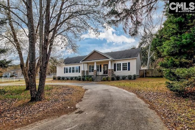 craftsman-style home featuring driveway and fence