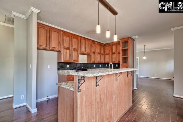 kitchen with dark wood finished floors, backsplash, crown molding, and light stone countertops