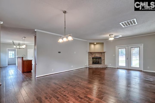 unfurnished living room featuring visible vents, a textured ceiling, a stone fireplace, and dark wood-style floors