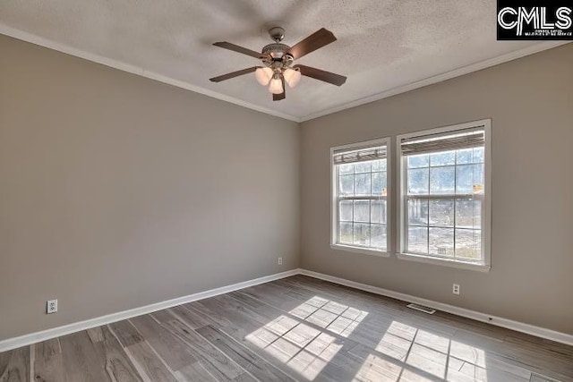 empty room featuring crown molding, wood finished floors, baseboards, and a textured ceiling