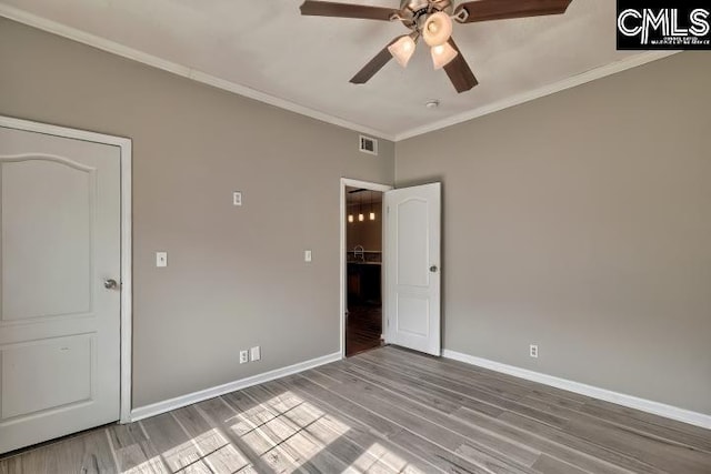 unfurnished room featuring visible vents, crown molding, baseboards, and wood finished floors