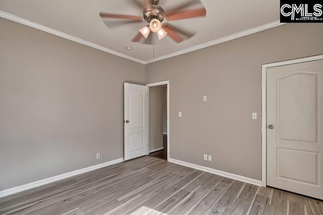 empty room with baseboards, a ceiling fan, wood finished floors, and crown molding