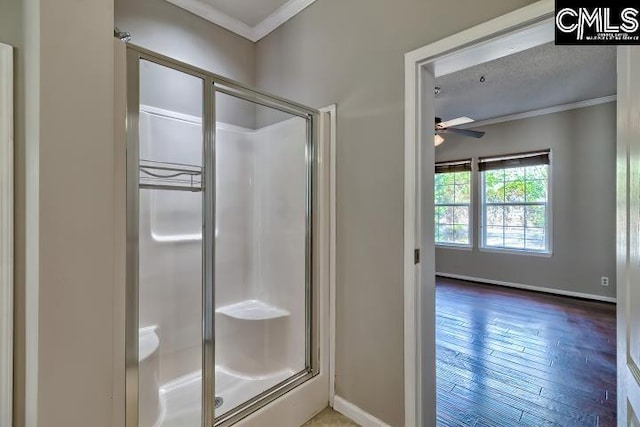 bathroom with a shower stall, crown molding, baseboards, and wood finished floors