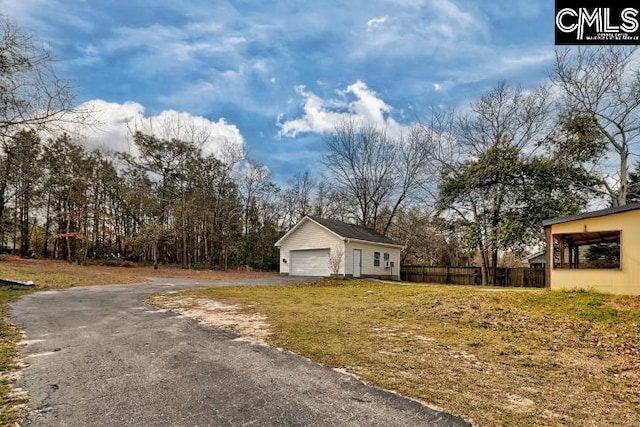 exterior space featuring a garage, an outdoor structure, driveway, and fence