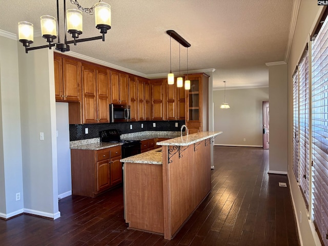 kitchen with dark wood-style floors, crown molding, black range with electric stovetop, stainless steel microwave, and brown cabinets