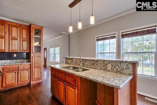 kitchen with a sink, backsplash, dark wood-style floors, and brown cabinetry