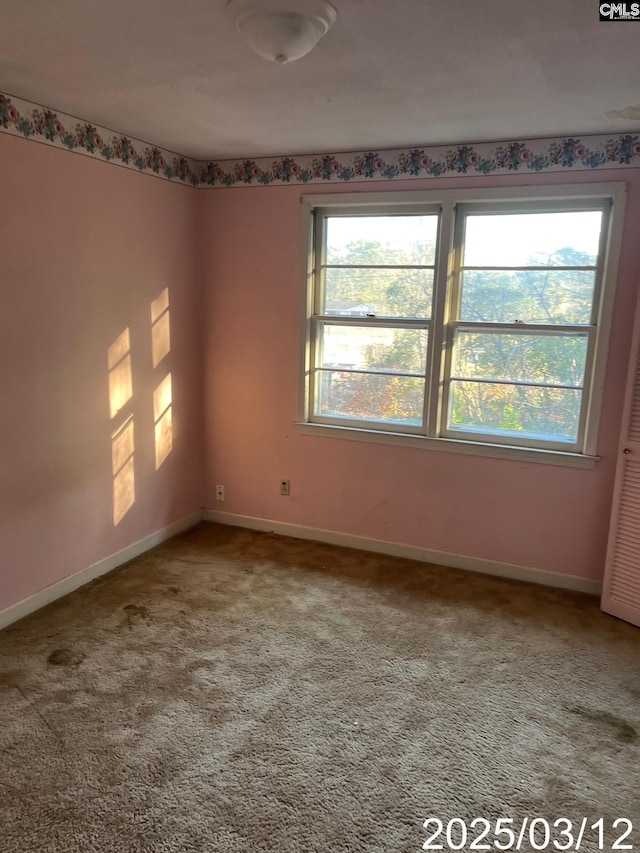 unfurnished room featuring plenty of natural light, baseboards, and carpet