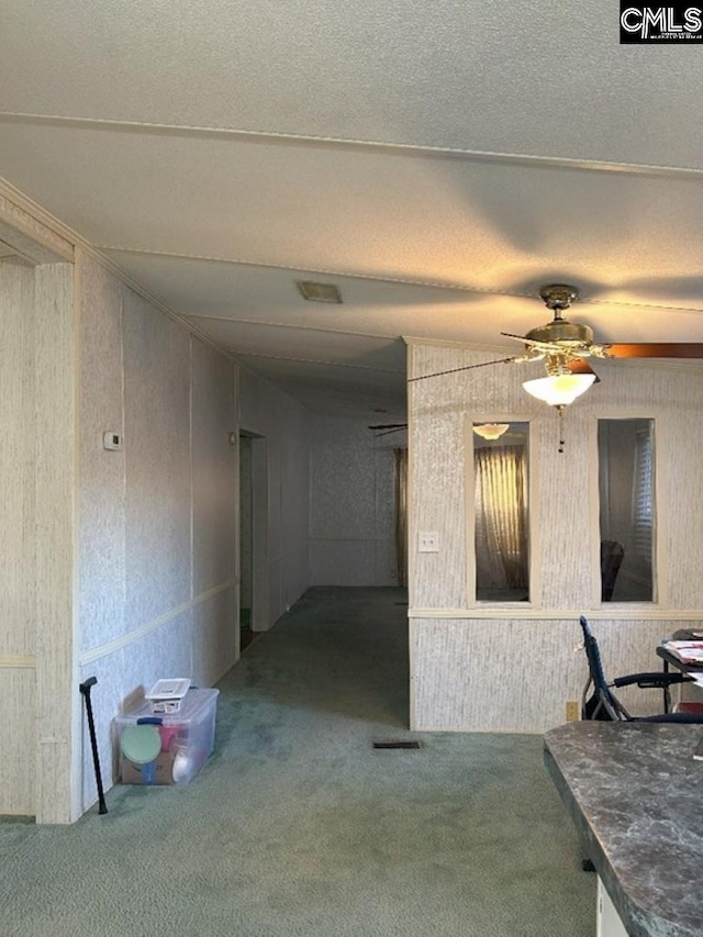 interior space with a textured ceiling, a ceiling fan, and carpet floors