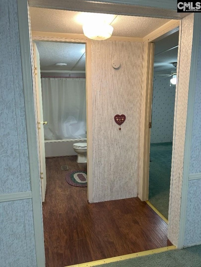 full bathroom featuring a textured ceiling, toilet, shower / tub combo, and wood finished floors