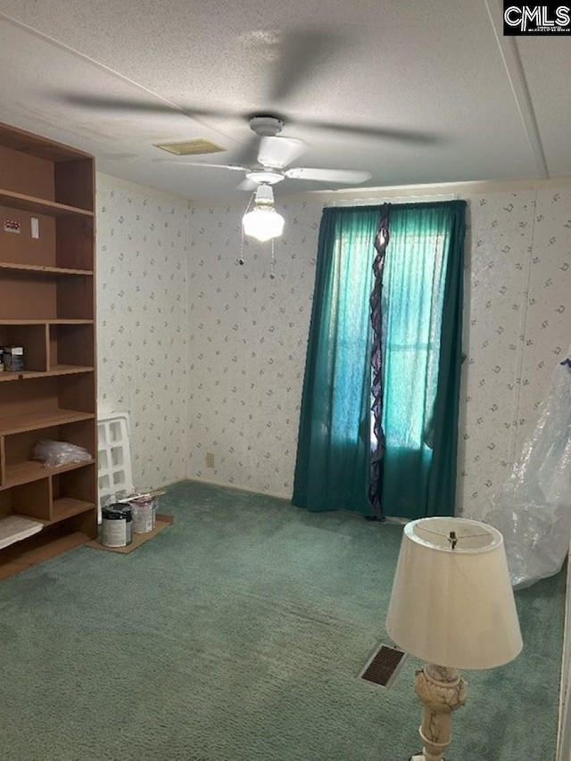 carpeted spare room featuring wallpapered walls, visible vents, and a textured ceiling