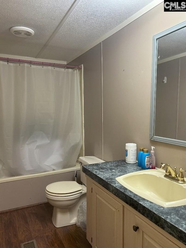 full bath featuring visible vents, toilet, vanity, wood finished floors, and a textured ceiling