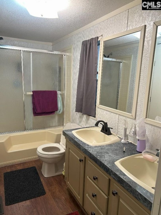 full bath with an enclosed shower, wallpapered walls, a textured ceiling, and a sink