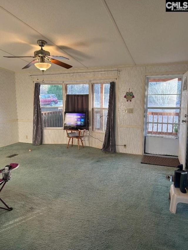 unfurnished living room with wallpapered walls, carpet, and ceiling fan