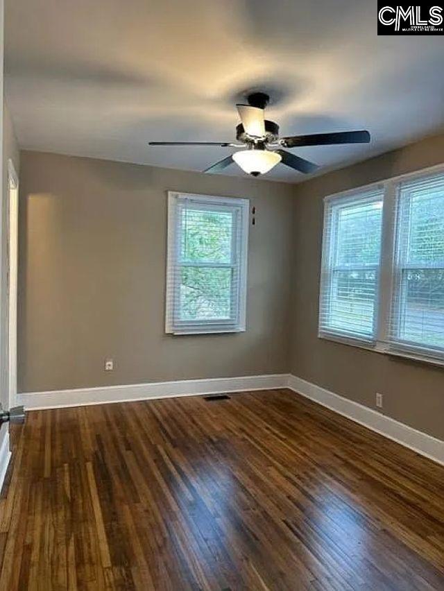 spare room with visible vents, baseboards, plenty of natural light, and dark wood-style floors