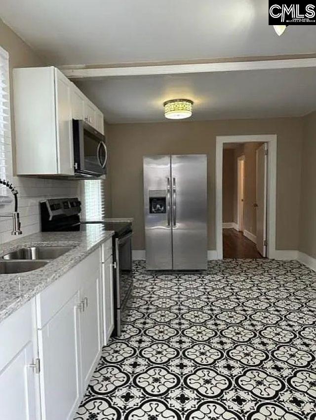 kitchen with a sink, tasteful backsplash, white cabinetry, stainless steel appliances, and baseboards