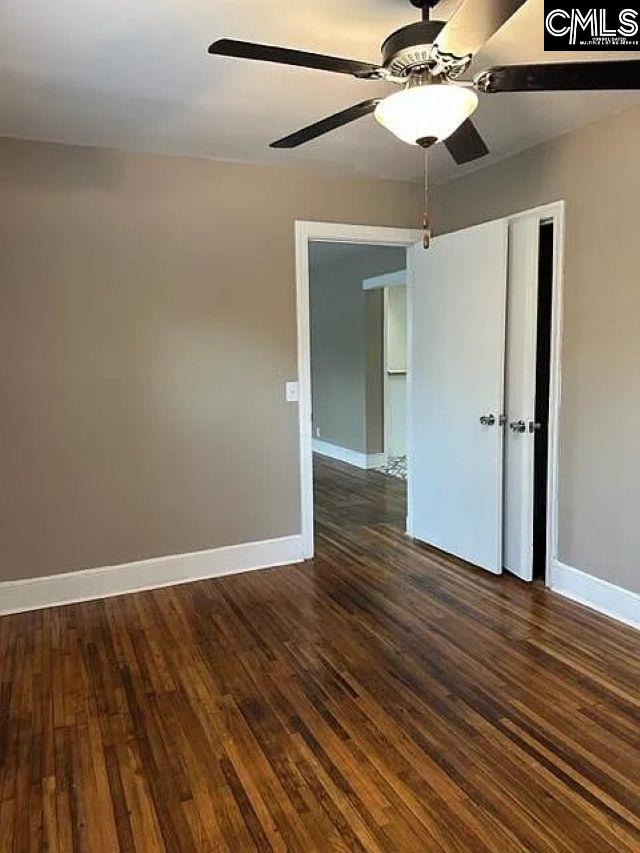 unfurnished room featuring dark wood finished floors, ceiling fan, and baseboards