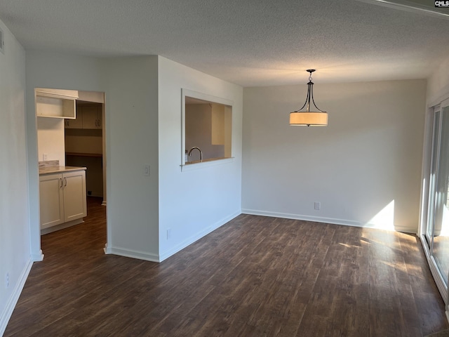 unfurnished room featuring baseboards, a textured ceiling, and dark wood-style flooring