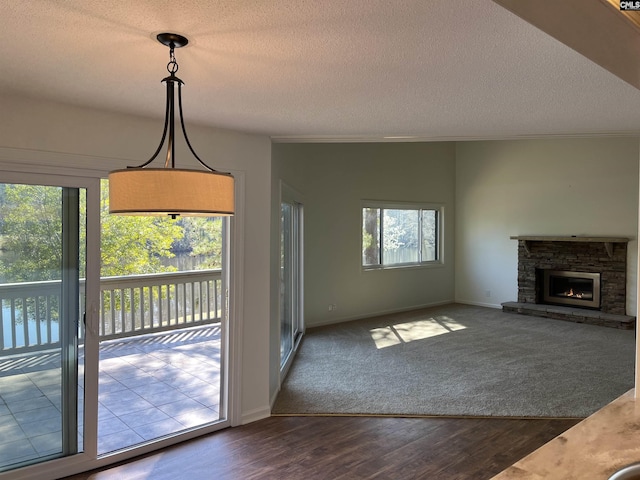 unfurnished living room featuring baseboards, ornamental molding, a stone fireplace, dark wood-style floors, and a textured ceiling