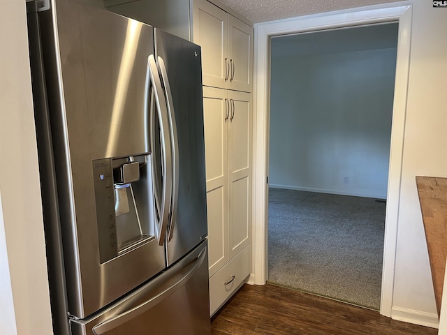 kitchen with dark wood-type flooring, dark carpet, stainless steel refrigerator with ice dispenser, a textured ceiling, and white cabinetry