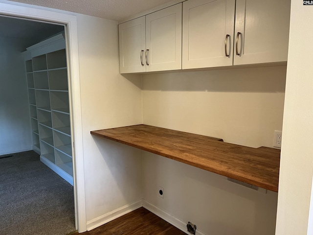 unfurnished office with baseboards, a textured ceiling, and built in desk