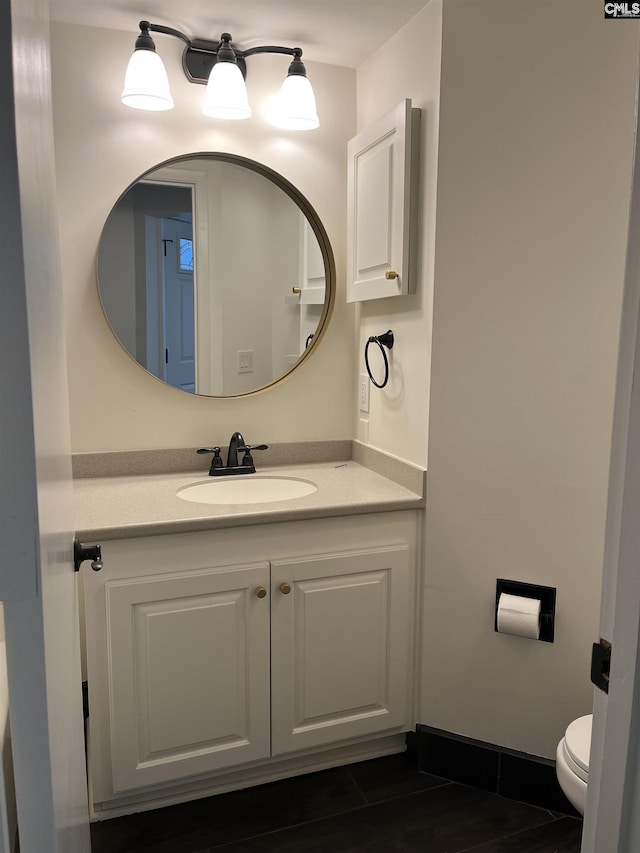 bathroom featuring baseboards, toilet, and vanity