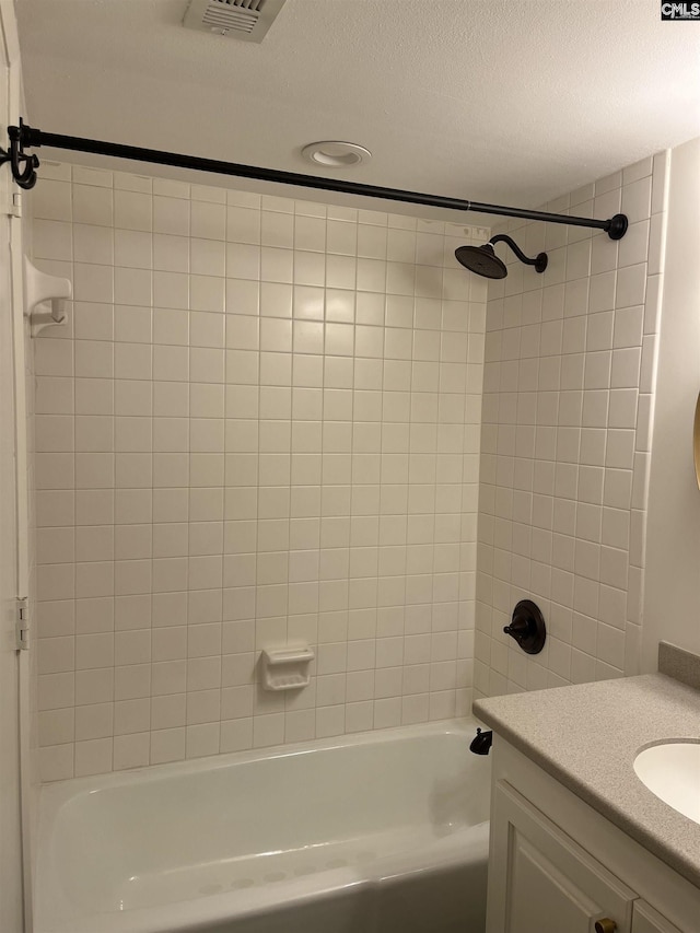 bathroom with vanity, a textured ceiling, visible vents, and shower / washtub combination