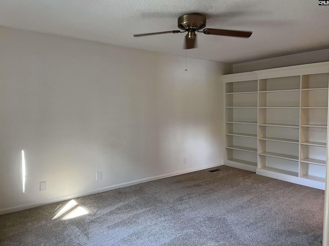 carpeted empty room with visible vents, a textured ceiling, baseboards, and a ceiling fan