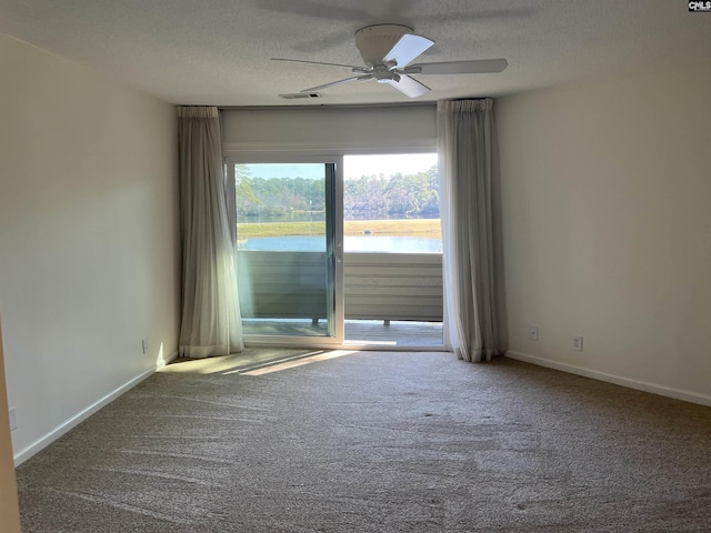 carpeted empty room with a textured ceiling, a ceiling fan, baseboards, and a water view