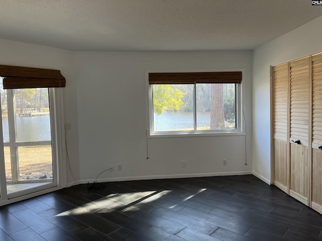 unfurnished bedroom featuring a textured ceiling, baseboards, and wood finish floors