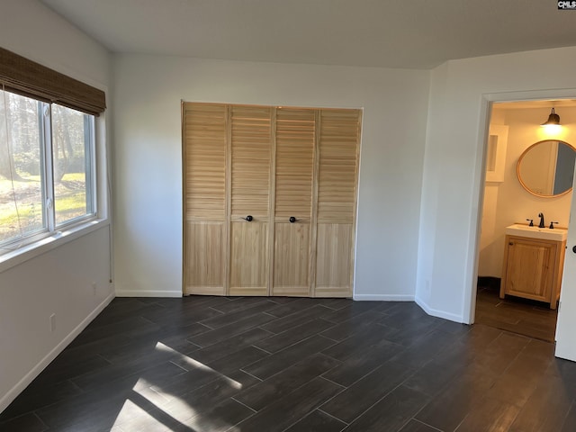 unfurnished bedroom with baseboards, dark wood-style flooring, and a sink