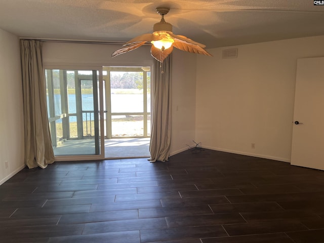 empty room featuring visible vents, a textured ceiling, baseboards, and wood tiled floor