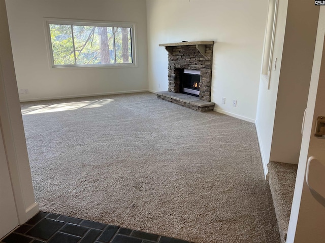 unfurnished living room with baseboards, carpet, and a fireplace