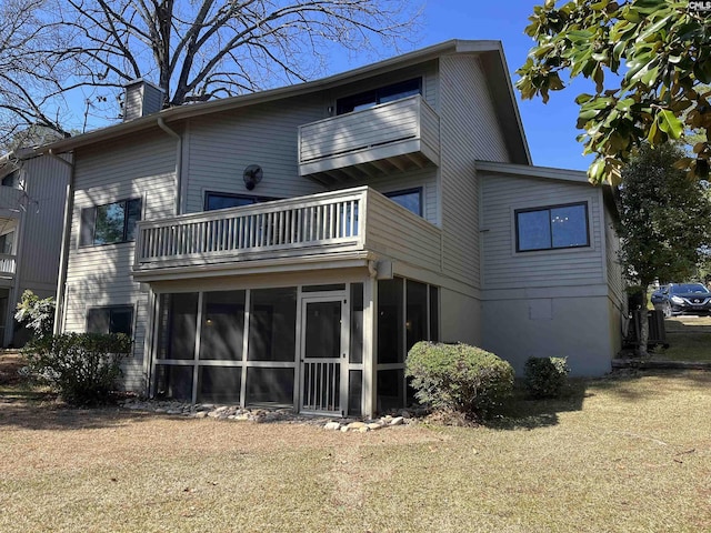 rear view of property featuring a balcony, a sunroom, and a chimney