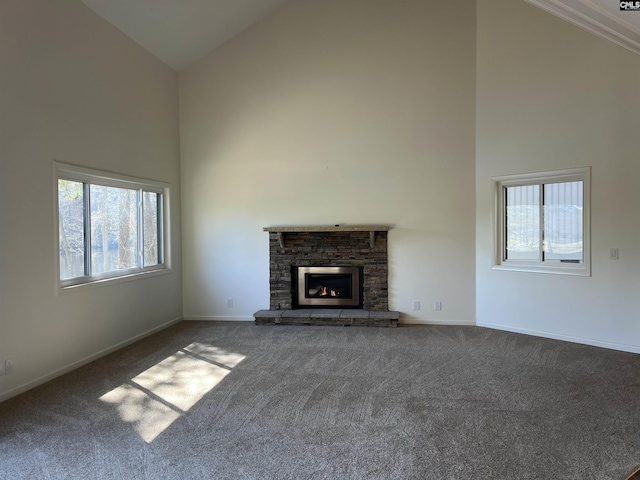 unfurnished living room with a stone fireplace, a healthy amount of sunlight, high vaulted ceiling, and carpet flooring