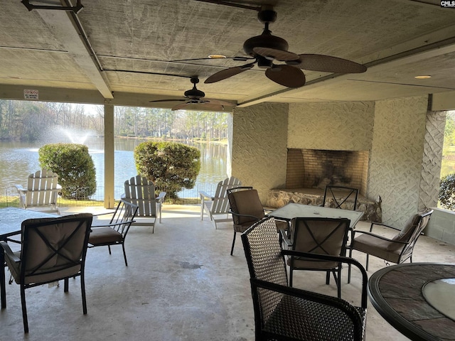 view of patio / terrace featuring outdoor dining space, a water view, and ceiling fan