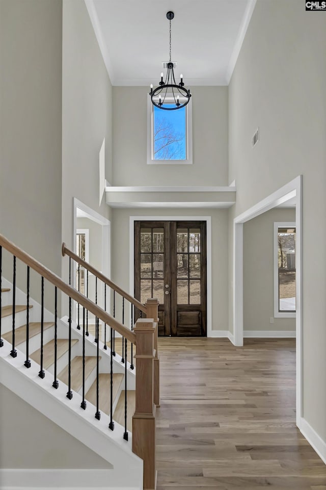 foyer entrance featuring stairway, wood finished floors, visible vents, ornamental molding, and french doors