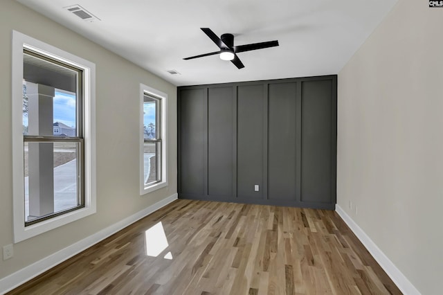 unfurnished bedroom with visible vents, baseboards, light wood-style flooring, and a decorative wall